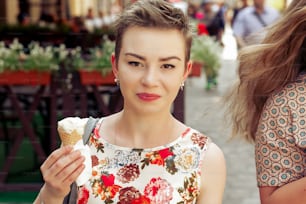 stylish happy woman holding vanilla ice-cream in hands, partying in city street, joyful moments