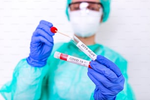 COVID-19 Teste laboratorial de swab nasal em laboratório hospitalar, Enfermeira segurando tubo de ensaio com sangue para análise de 2019-nCoV. Novo Conceito de exame de sangue chinês de coronavírus.