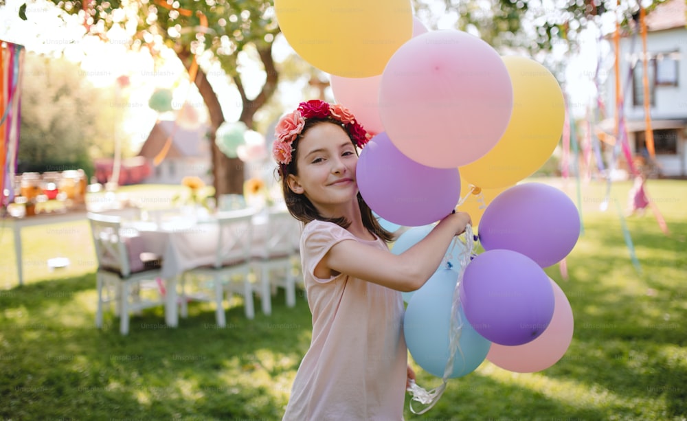 Piccola ragazza all'aperto in giardino in estate, giocando con i palloncini. Un concetto di celebrazione.