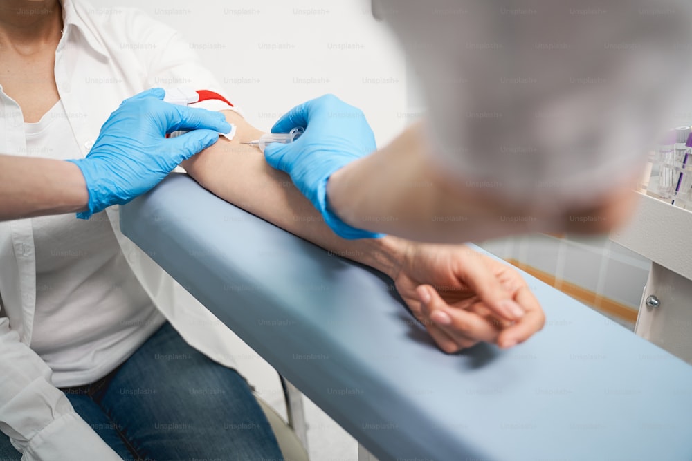 Chequeo médico. Paciente joven visitando a su terapeuta mientras hace un chequeo de salud, toma muestras de sangre para análisis