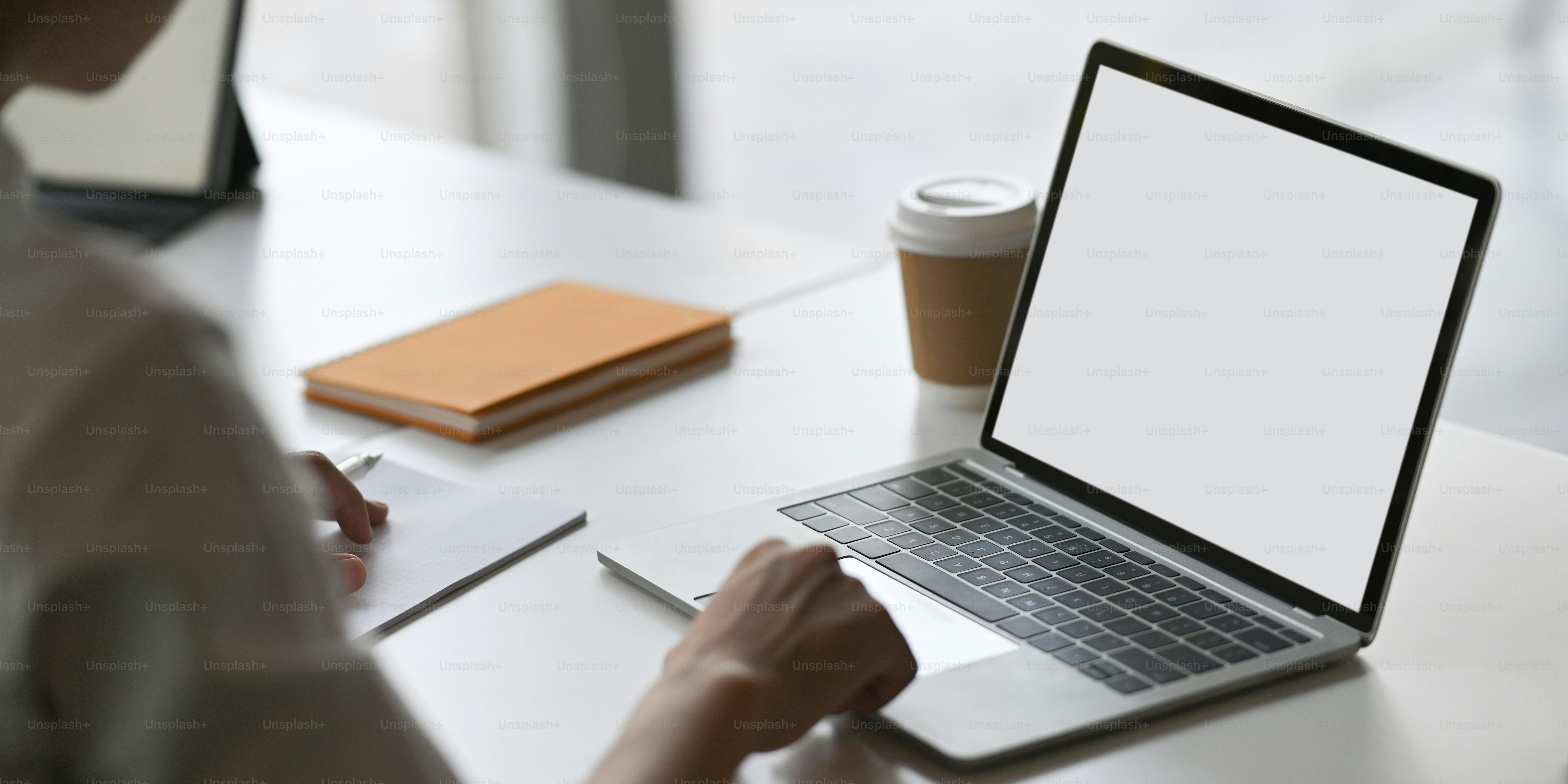 Imagem recortada de homem bonito usando um laptop de computador com tela  branca em branco enquanto sentado na mesa de trabalho branca sobre a  confortável sala de estar como fundo. foto –, image size:3000x1500