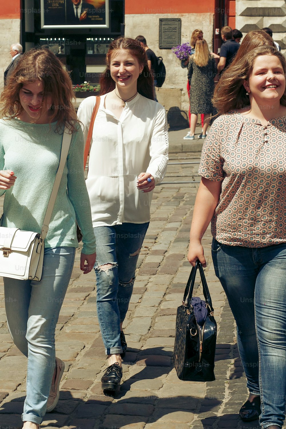 Molte giovani donne felici che camminano parlando sullo sfondo della vecchia strada della città europea, ragazze hipster alla moda che si divertono, momenti di felicità, concetto di amicizia