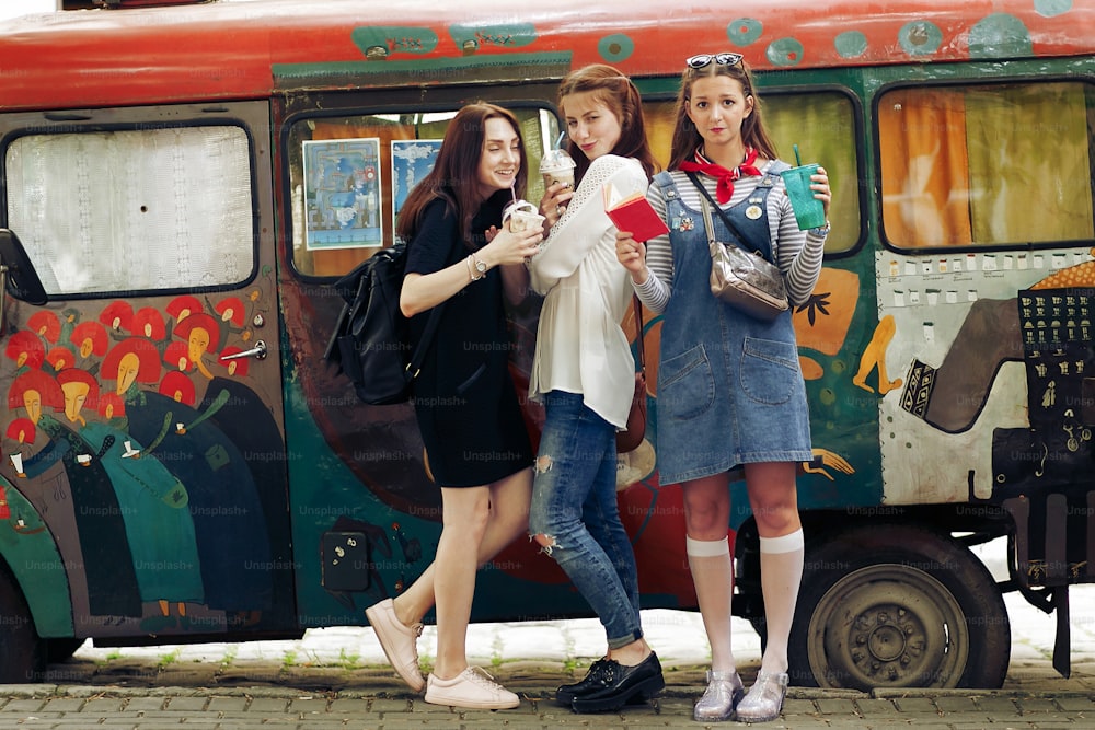 stylish happy group of women holding ice-cream and cocktails in hands and having fun, relaxing in city street, joyful moments