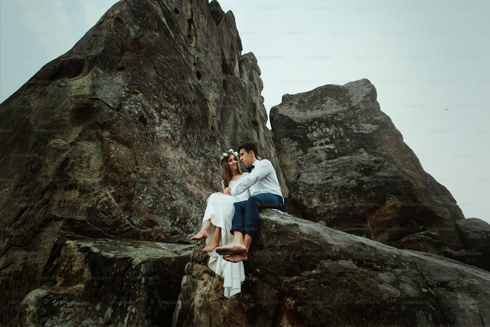 happy beautiful bride and elegant stylish groom  hugging on rocks on the background of sunset mountains