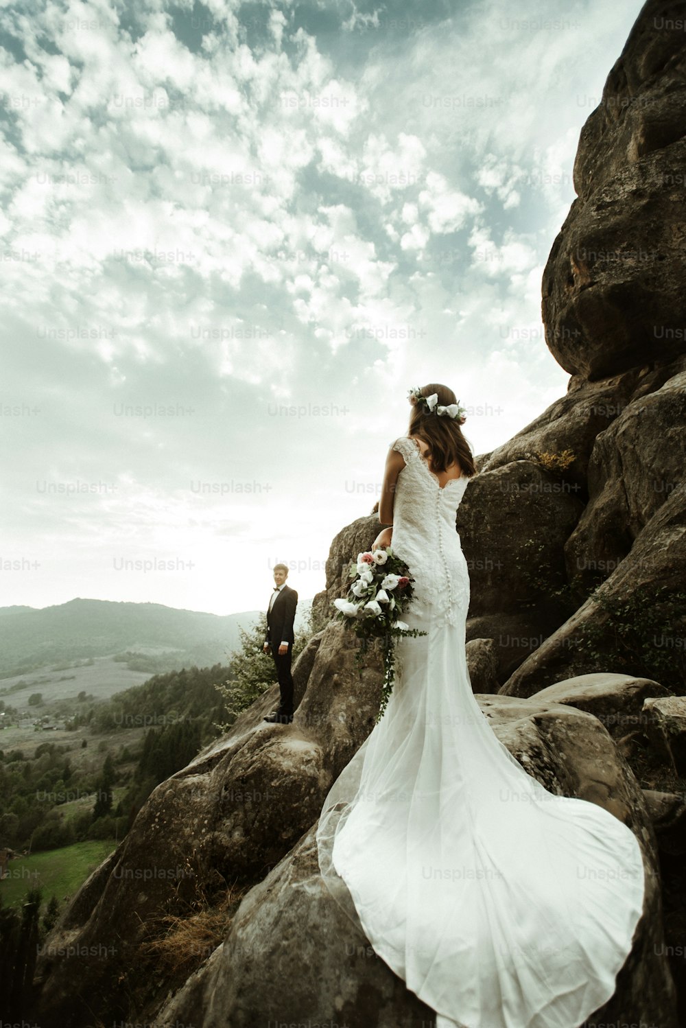 noiva feliz de luxo e noivo elegante posando no fundo de rochas ensolaradas e céu em montanhas incríveis