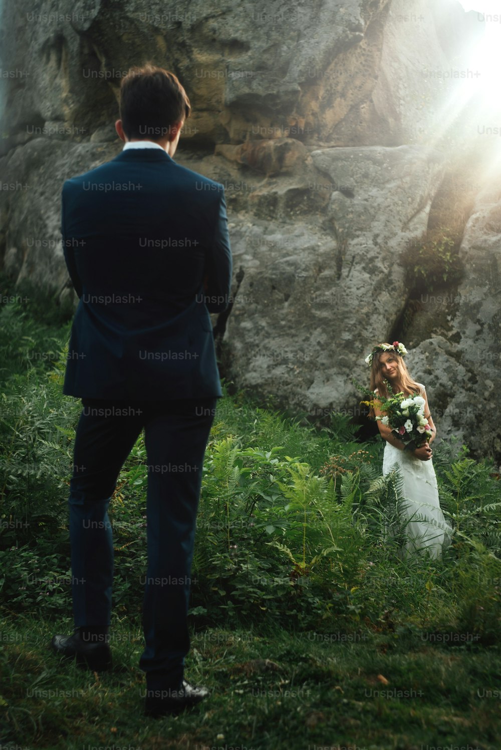 elegante novia boho sosteniendo y elegante novio feliz en el fondo de rocas en las montañas