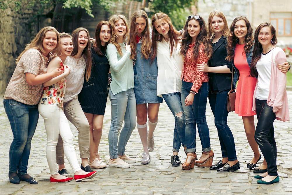 Group of happy stylish women posing on background of old european city street, travel or celebrating friendship concept, moments of happiness