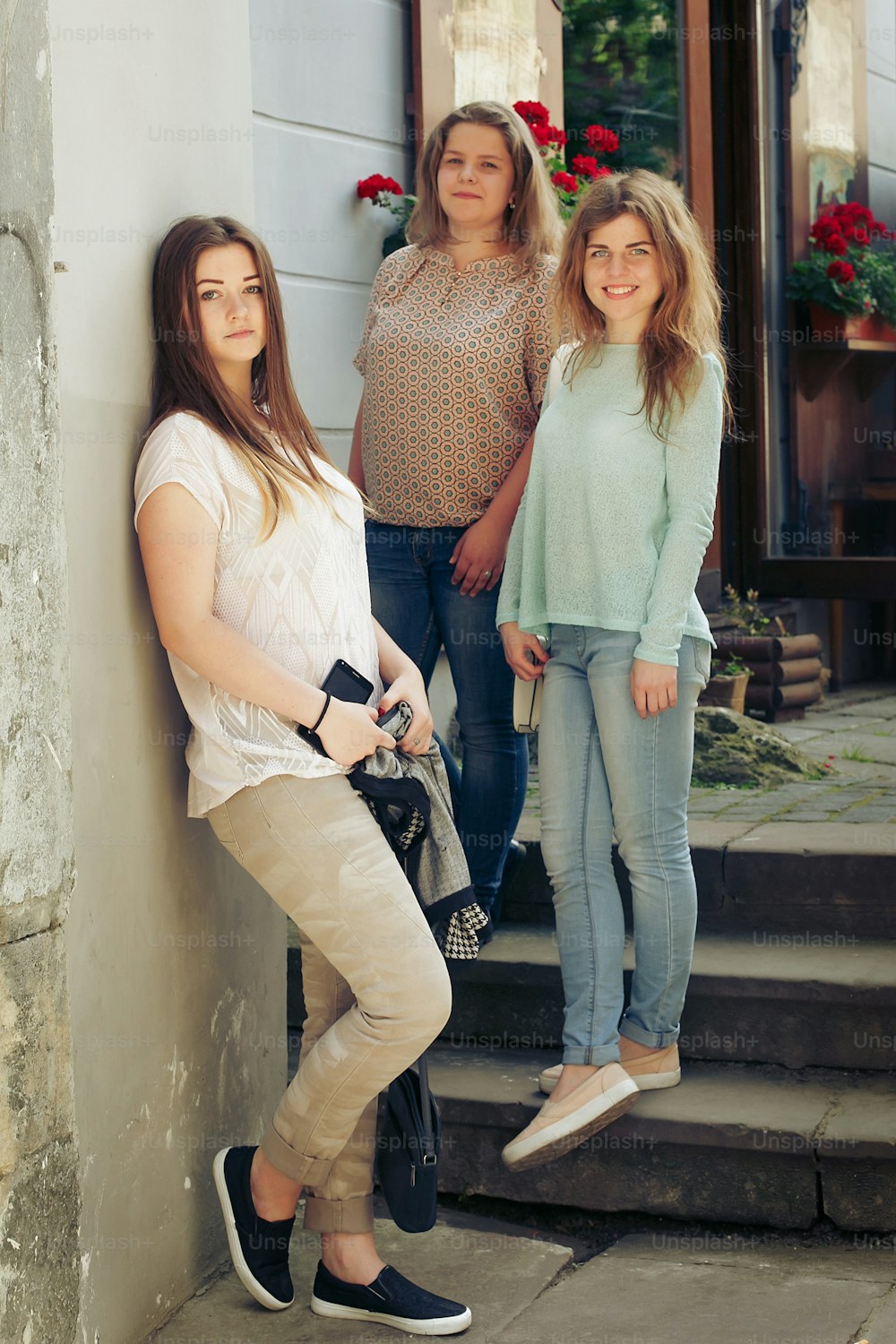 Tre hipster alla moda della donna felice alla moda vestiti in posa nella strada della città dell'Europa, concetto di amicizia di momenti gioiosi
