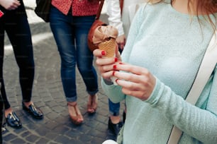 ice cream in hand. Group of women holding chocolate and pink ice-cream in hands close-up, partying and having fun  in city street