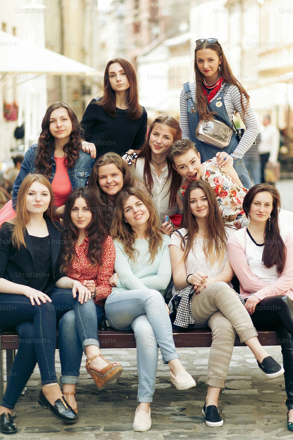 stilvolle glückliche Frauen Hipster modisch gekleidet lächelnd und auf der Bank sitzen in Europa City Street, freudige Momente Freundschaft Konzept