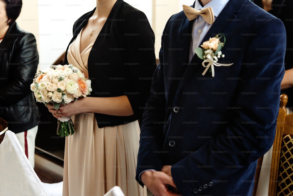 chauffeur élégant et demoiselle d’honneur tenant un bouquet lors d’une cérémonie de mariage à l’église