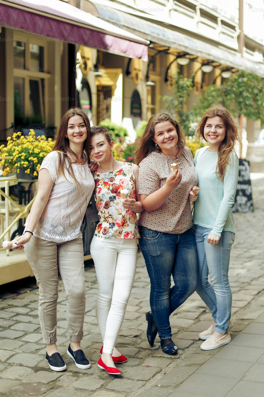 Group of happy women holding ice-cream in hands and having fun, partying in city street, joyful moments