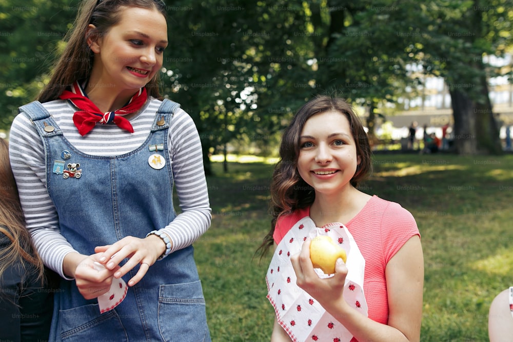 Stilvolle glückliche Gruppe von Frauen, die Früchte essen und Spaß beim Picknick haben, freudige Momente im Sommerpark