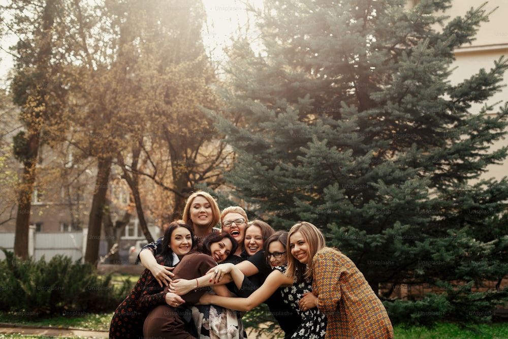 stylish elegant women having fun at celebration in sunny park, funny moment concept, gathering together