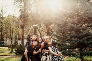 공원에서 햇볕이 잘 드는 축하 행사에서 재미있는 셀카를 찍는 세련된 우아한 여성들, 럭셔리 해피 라이프 컨셉