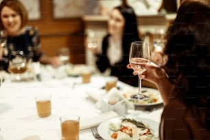 Mano de la mujer con estilo que sostiene una copa de champán y brinda en la celebración de lujo en el restaurante