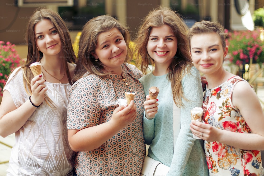 Grupo de mulheres felizes segurando sorvete nas mãos e se divertindo, festejando na rua da cidade, momentos alegres