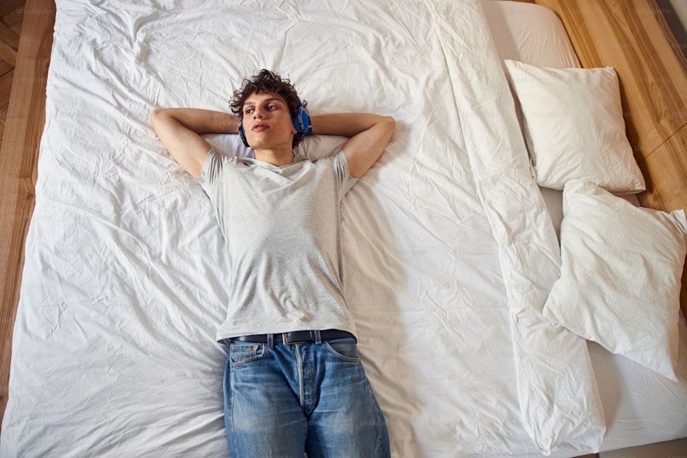 Handsome young man lying on bed and enjoying favorite songs stock photo