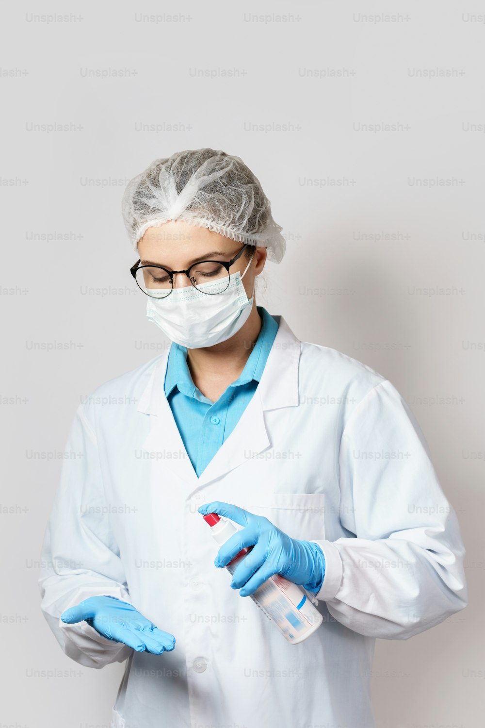 La joven doctora realiza una desinfección adicional de los guantes con un spray de alcohol