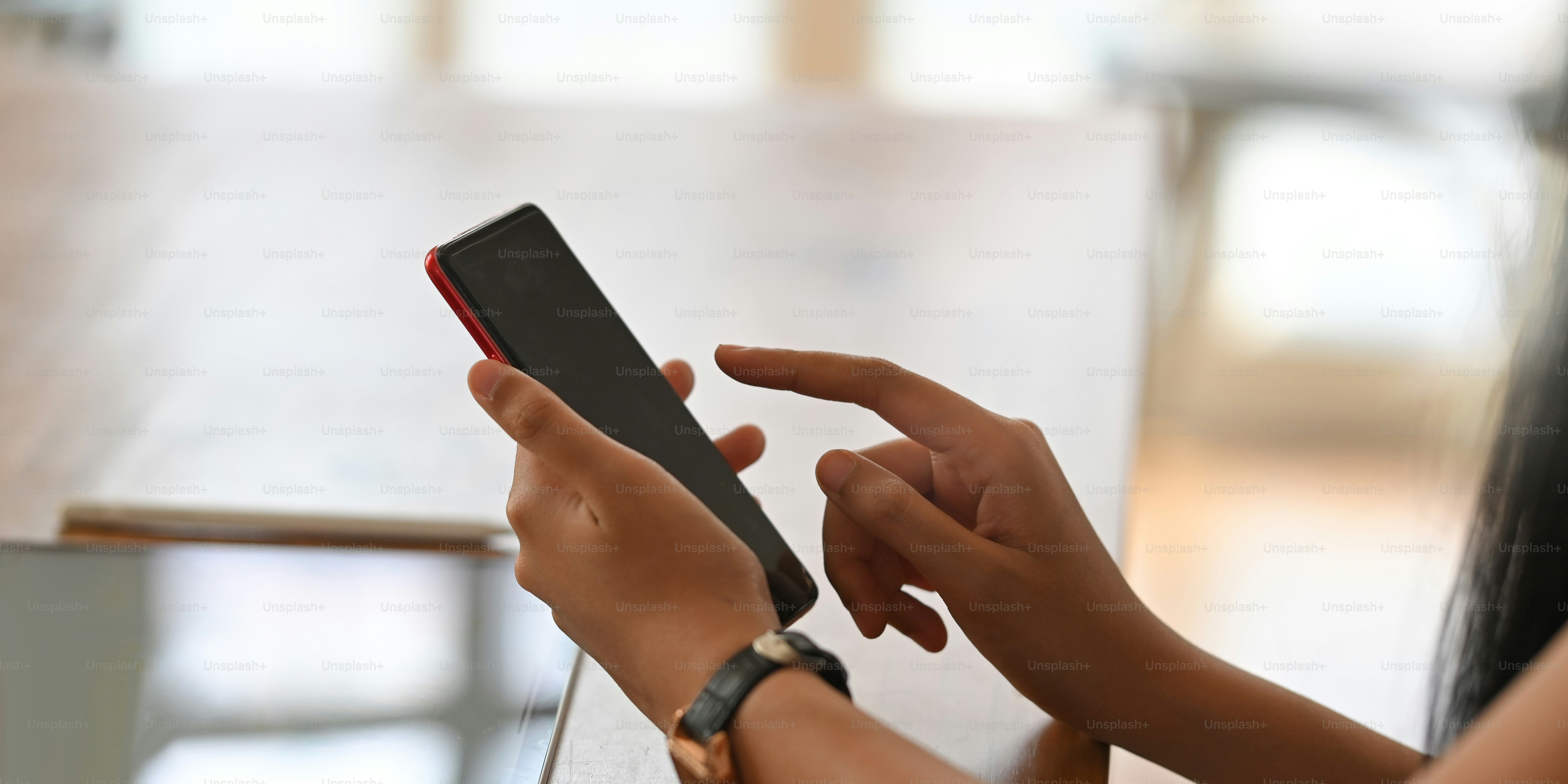 Immagine ritagliata di belle mani di donna che utilizzano/tengono uno smartphone mentre sono sedute alla scrivania di lavoro in legno. Donna con concetto di tempo rilassante.