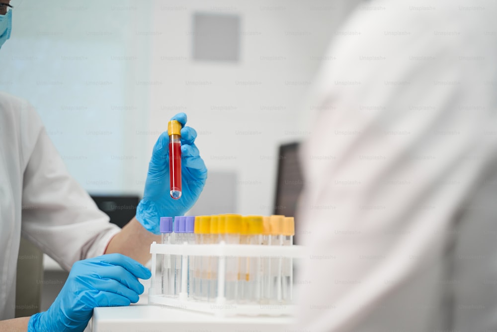 Professional consultation. Competent researcher wearing protective uniform while working in modern laboratory with test tubes