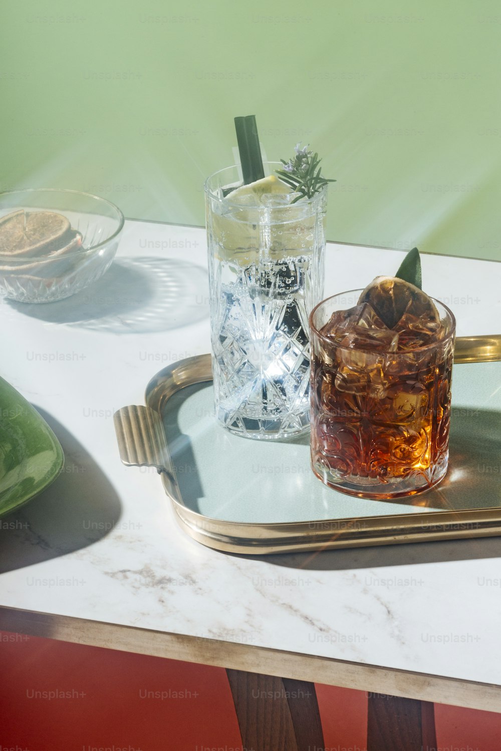 Gin tonic e cocktail Negroni, con arancia carbonizzata, fetta di limone e rosmarino in fiore, su un tavolino. Estetica vintage