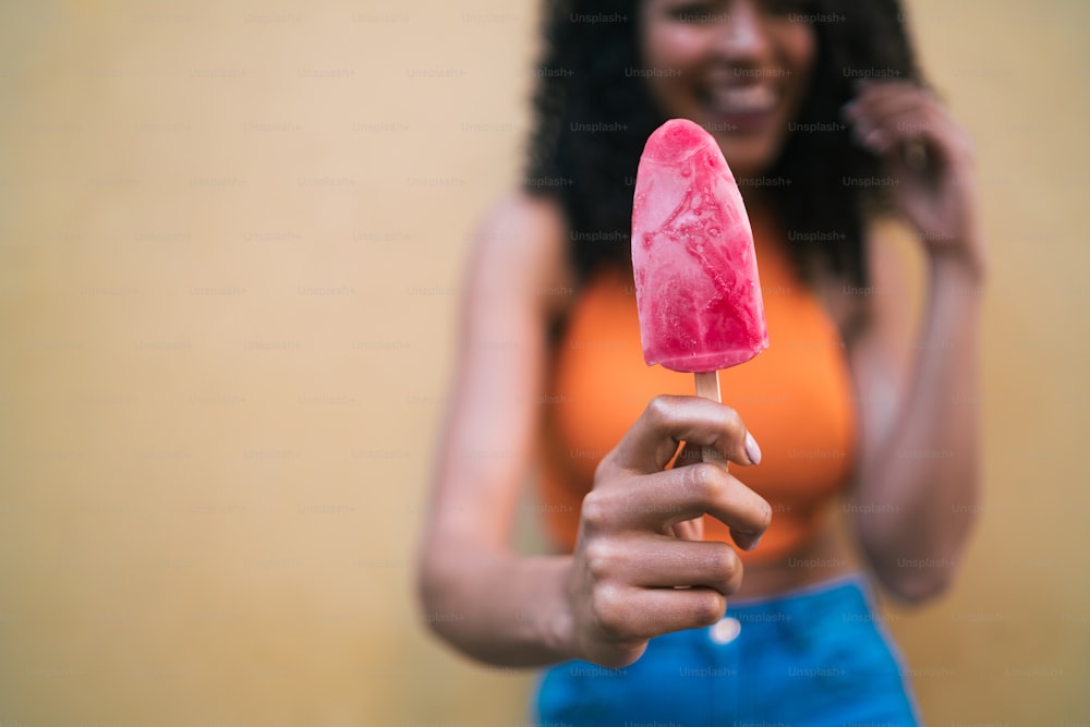 Portrait of young afro american woman enjoying summertime and eating an ice-cream. Lifestyle concept.