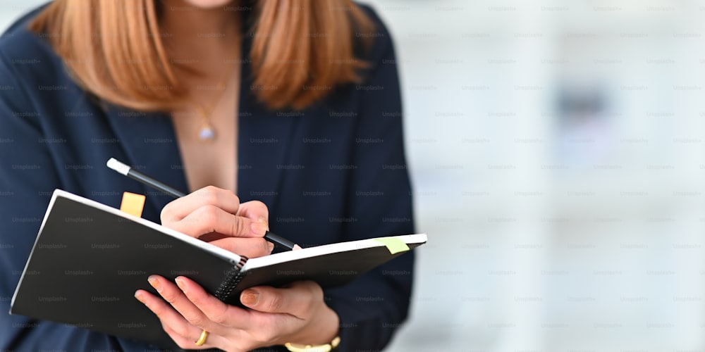 Cropped image of beautiful woman working as secretary taking note while sitting in comfortable cafe as background. Comfortable workplace concept.