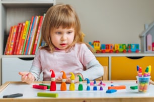 Bambina che modella gnomi colorati dall'argilla da gioco per bambini sul tavolo nella stanza dei bambini. Attività a domicilio per la famiglia." n