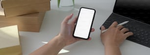 Cropped shot of start up businesspeople working with mock-up smartphone, tablet and boxes on white table