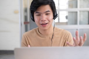 Online-Meeting und Arbeiten zu Hause oder im Büro. Glücklicher junger Mann, der spricht und Laptop für Videokonferenz benutzt.