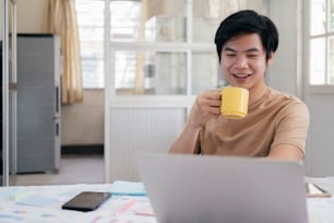 Il giovane si rilassa con una tazza di caffè e usando il computer portatile a casa.