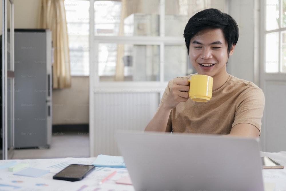 Young man relax with a cup of coffee and using computer laptop at home.
