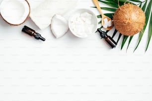Flache Lay-Komposition mit Kokosölen und SPA-Zubehör auf weißem Hintergrund. Draufsicht natürliche Biokosmetik für feuchtigkeitsspendende Haut. Hautpflege, Schönheitsbehandlungskonzept