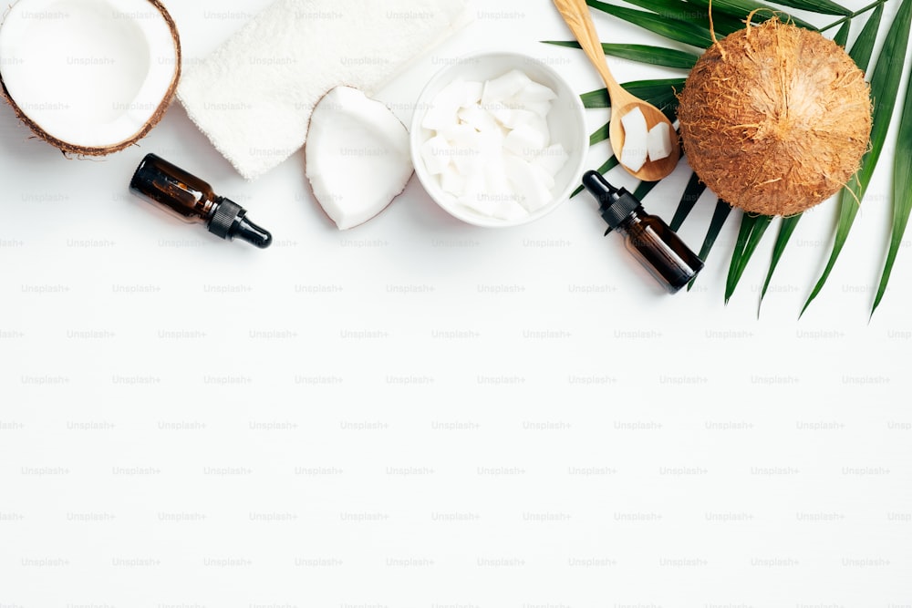 Flat lay composition with coconut oils and SPA accessories on white background. Top view natural organic cosmetic for skin moisturizing. Skin care, beauty treatment concept