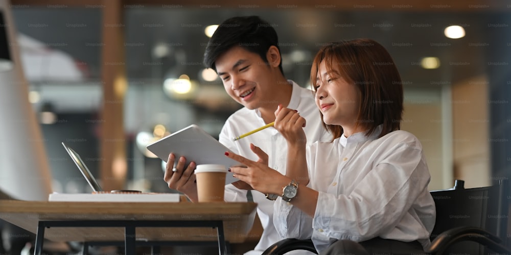 Young couple working together with computer laptop and document while sitting at the wooden working desk over comfortable cafe as background.
