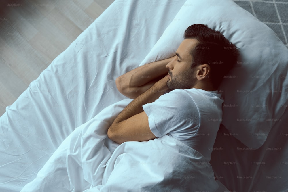 「枕の上に横たわり、朝の睡眠中のハンサムな穏やかな男性の上から見た写真素材」