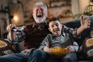 할아버지와 손자가 텔레비전을 보고 있다. 집에서 즐기는 할아버지와 손자.