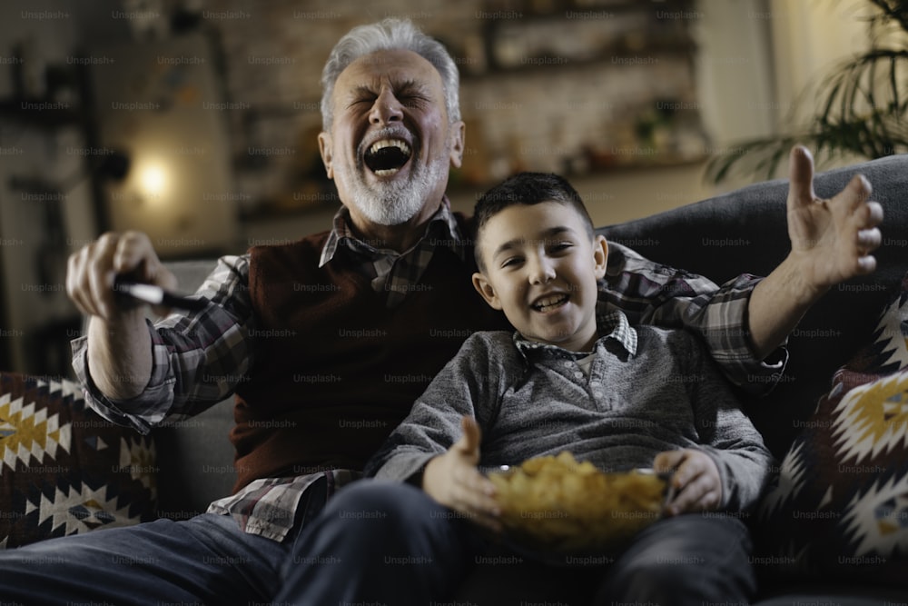 할아버지와 손자가 텔레비전을 보고 있다. 집에서 즐기는 할아버지와 손자.