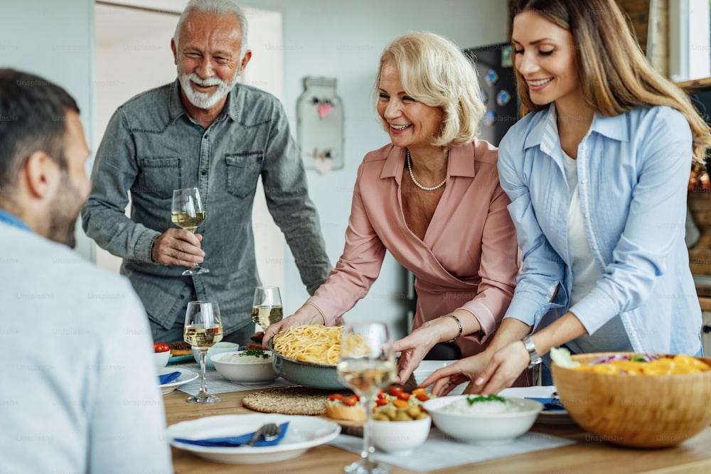 Famiglia felice che parla mentre fa i preparativi per un pranzo in famiglia a casa. L'attenzione è rivolta alla donna anziana.