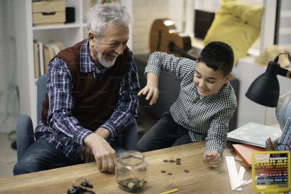 Grandpa and grandson saving money. Grandfather teaching grandchild how to save money.