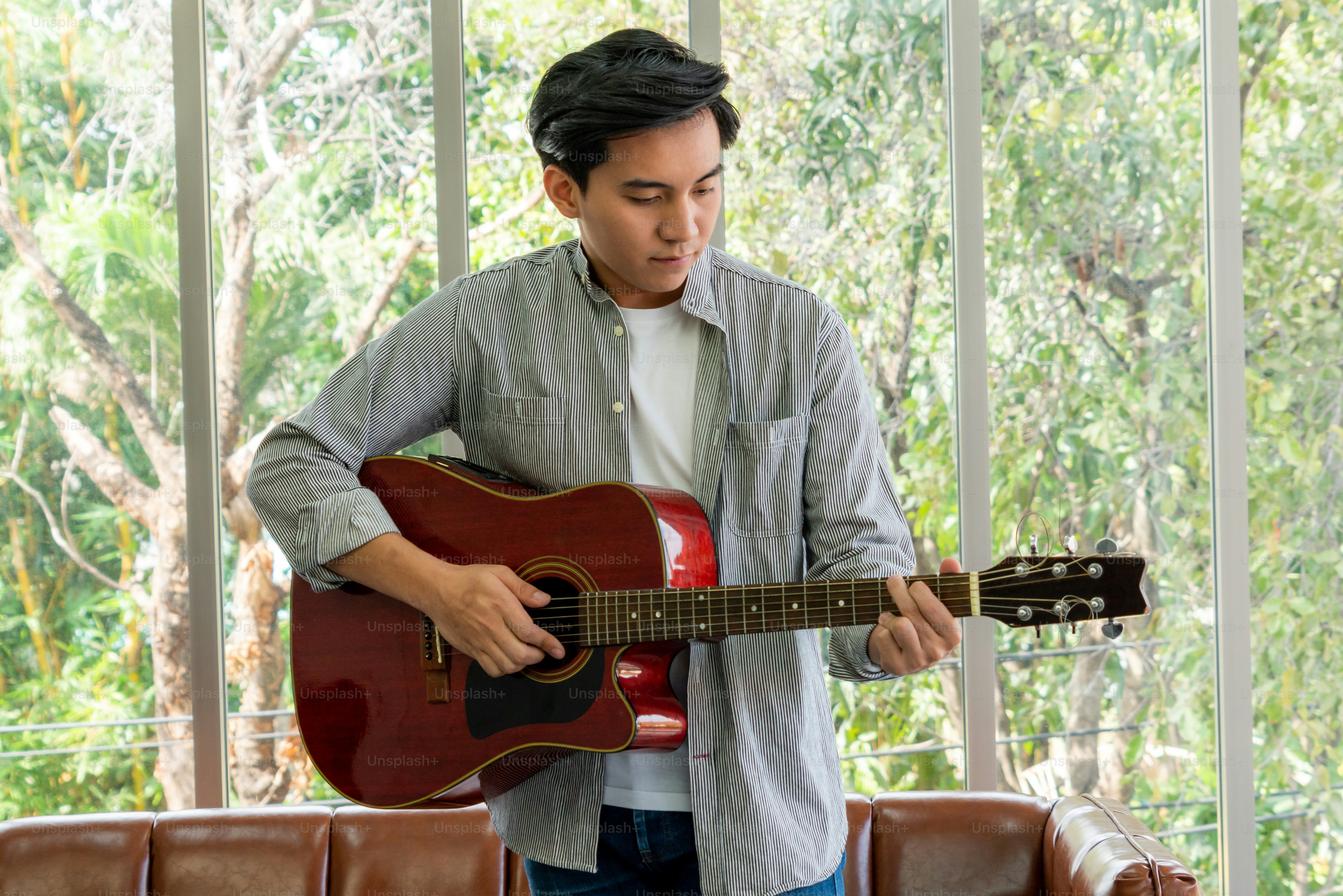 Jovem guitarrista segurando sua guitarra em casa. Música e conceito de canção.