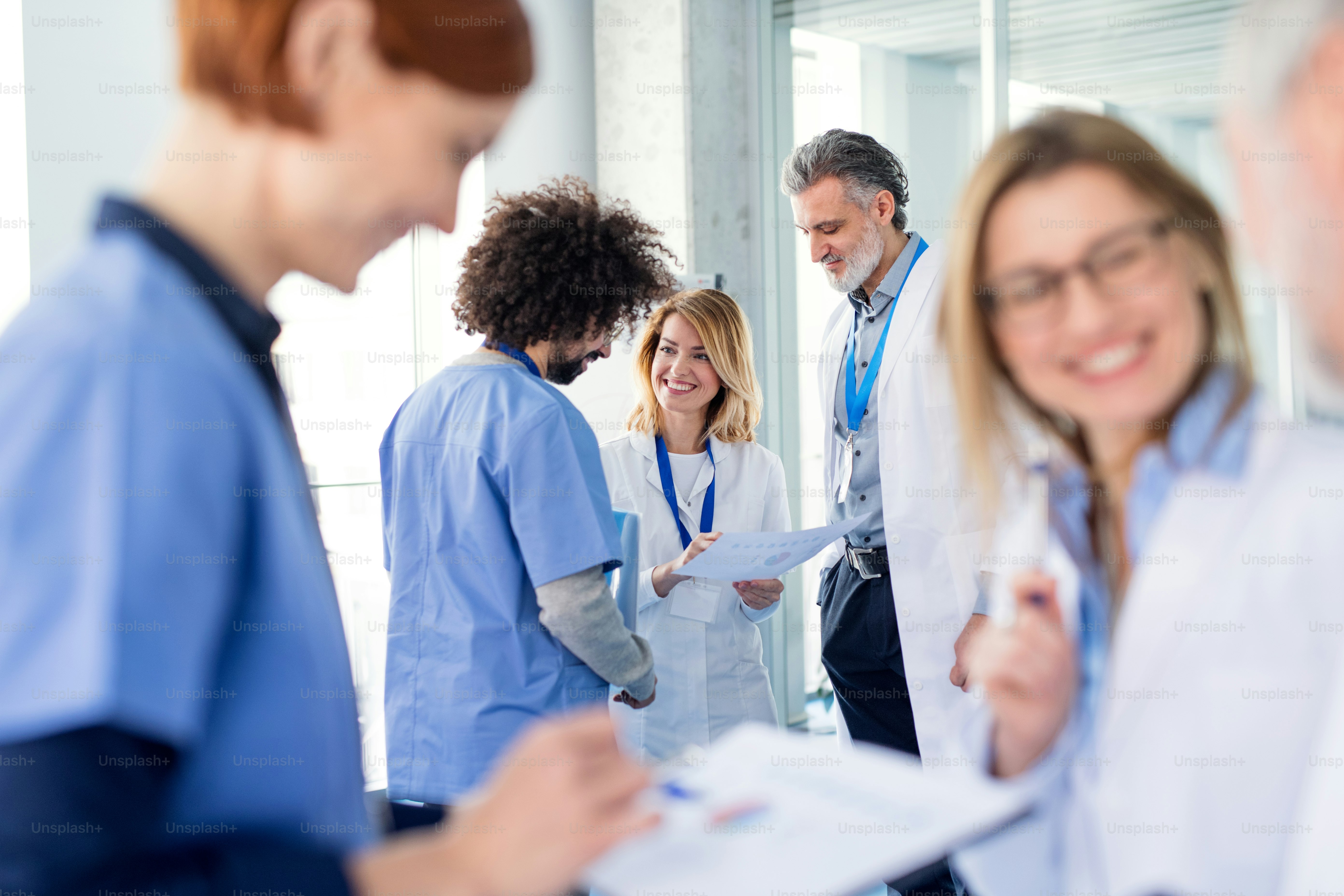 Groupe de médecins en conférence, équipe médicale debout et discutant des problèmes.