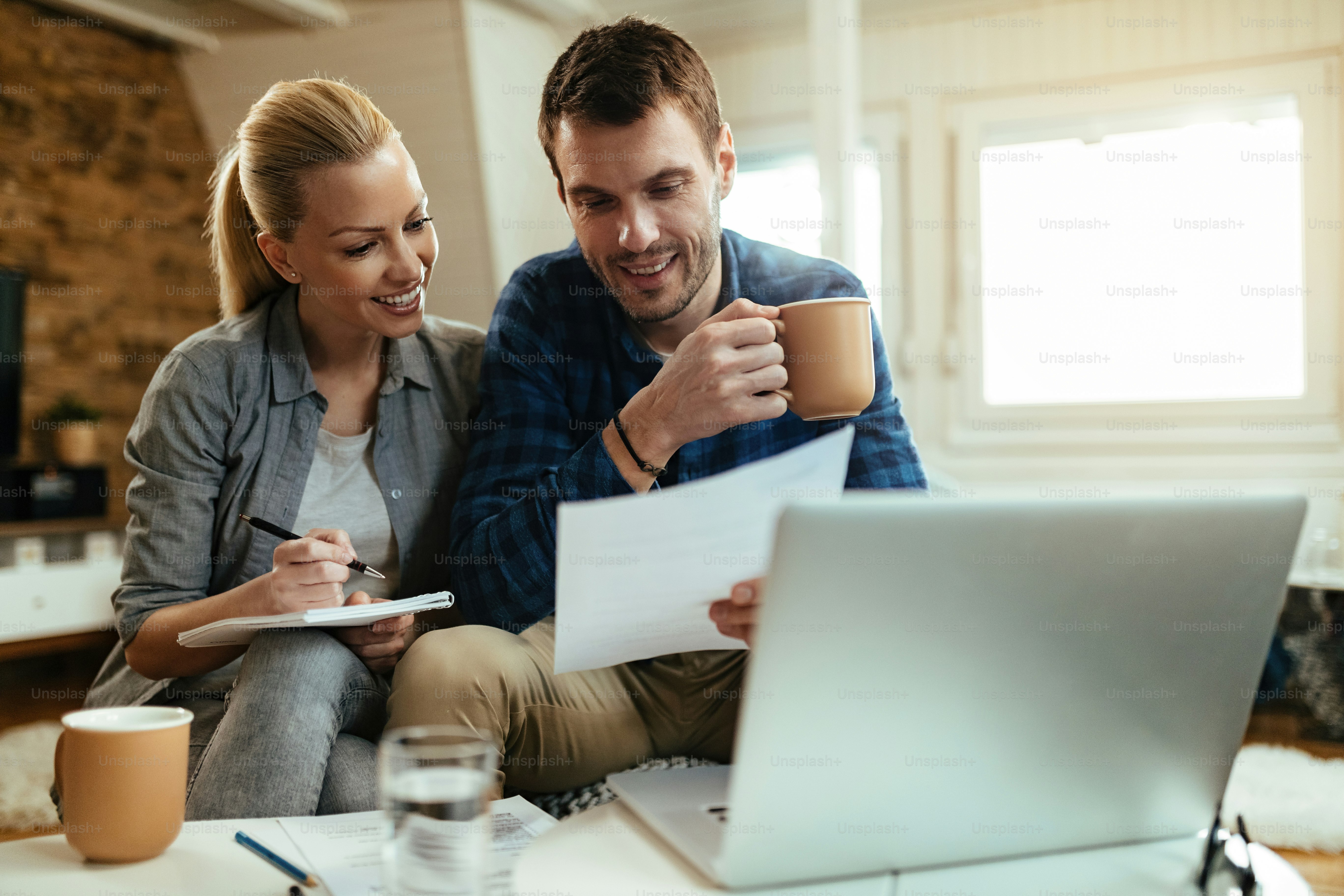 Happy couple going through paperwork while working together at home.