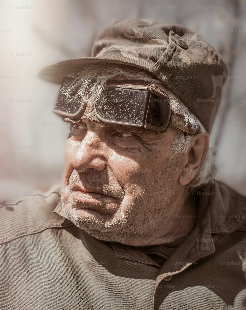 Hombre blanco anciano de ochenta años de edad con uniforme de trabajo y gafas protectoras viejas de trabajo para soldar. Arrugado en la cara y la ropa de trabajo. Ocio en la vejez