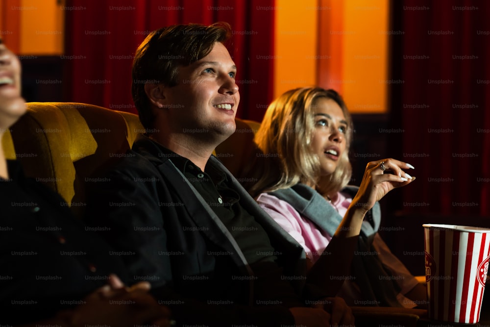 Amante caucasica e donna seduta accanto a loro che si diverte a guardare un film