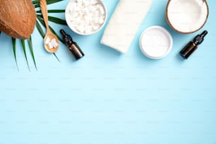 Frame of coconut oil cosmetics on blue background. Flat lay, top view. SPA natural organic products, skin care concept