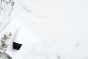 Flaconi di deodorante con eucalipto e asciugamano su sfondo di marmo. Posa piatta, vista dall'alto. Confezione antitraspirante bianca, concetto di prodotto per la protezione dal sudore