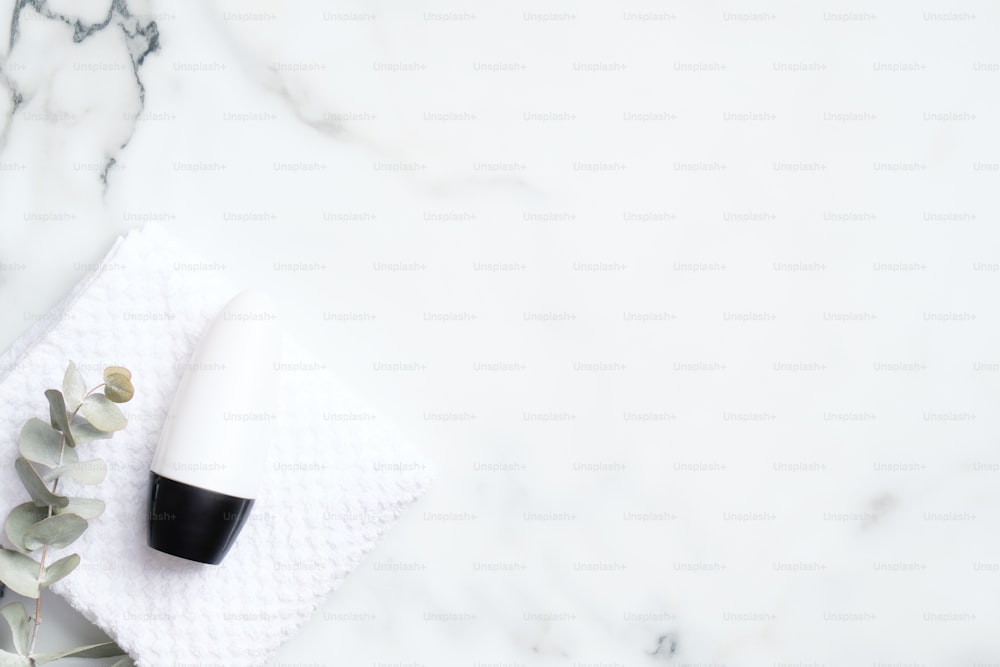 대리석 배경에 유칼립투스와 수건이 있는 데오도란트 병. 플랫 레이, 평면도. 백색 발한 억제제 포장, 땀 방지 제품 개념