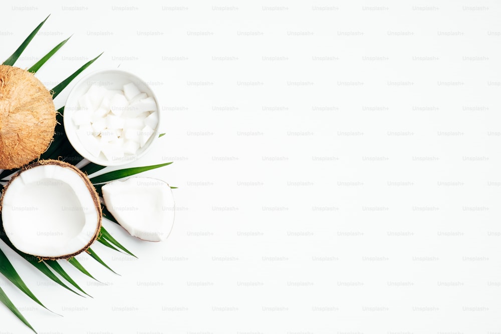 Summer background with coconut fruit and palm leaf on white background. Flat lay, top view, copy space